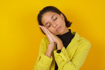 Young hispanic businesswoman wearing casual turtleneck sweater and jacket sleeping tired dreaming and posing with hands together while smiling with closed eyes.
