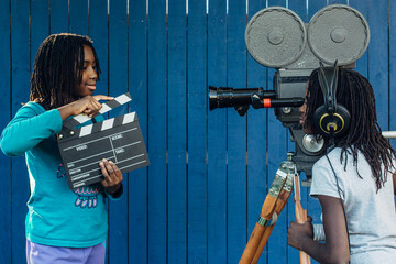 Two black girls doing a movie with an old 16mm film camera