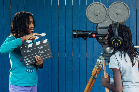Two black girls doing a movie with an old 16mm film camera