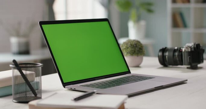 The table of distant worker at home. Modern laptop computer with chroma key green screen. Remote work, distance learning, technology concept close up 4k video template