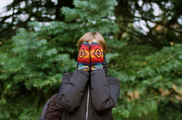 Woman closes her face with the mittens