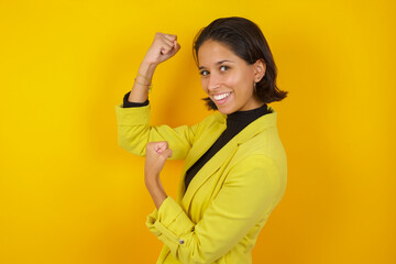 Profile photo of excited Young hispanic businesswoman wearing casual turtleneck sweater and jacket raising fists celebrating black friday shopping