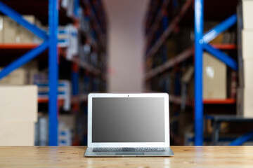 Personal laptop computer in warehouse store. Warehouse with Rows of Shelves and Cardboard Boxes