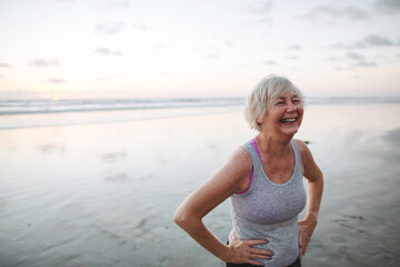 Vibrant mature woman enjoying herself on the beach at sunset