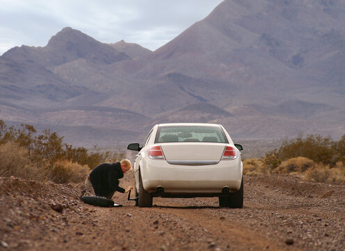 Driver with flat tire in a bad place - backroad in the desert