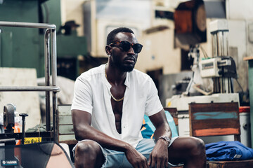 Portrait photo young stylish black man in a white T-shirt and glasses in old factory. Street photo. african american people.