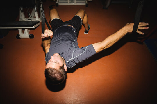 Young man doing exercises in a gym with straps