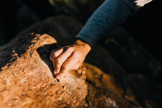 A man scratching a rock against a boulder