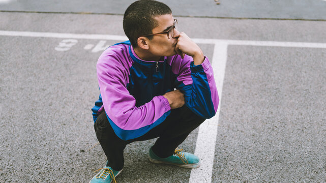 Young adolescents in colorful track suits from 90's in squat position.