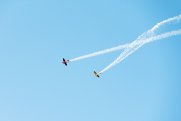 Planes dropping smoke and doing acrobatics on a clear blue sky with copy space.