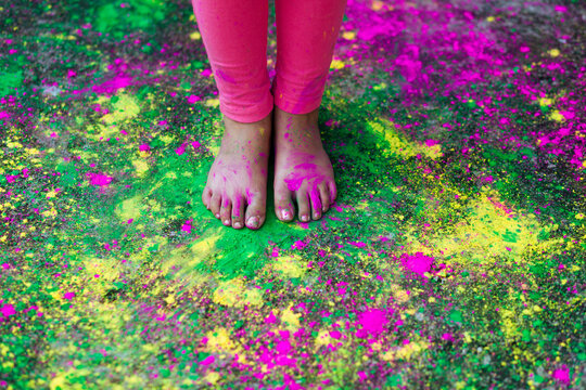 Little girl's feet on scattered multicolored rangoli on the floor
