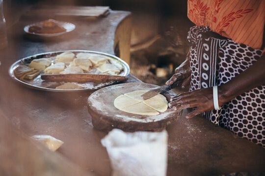 Rural African villager kneading dough and making bread and cooking in her kitchen