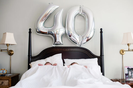 couple hiding under the covers on a 40th birthday