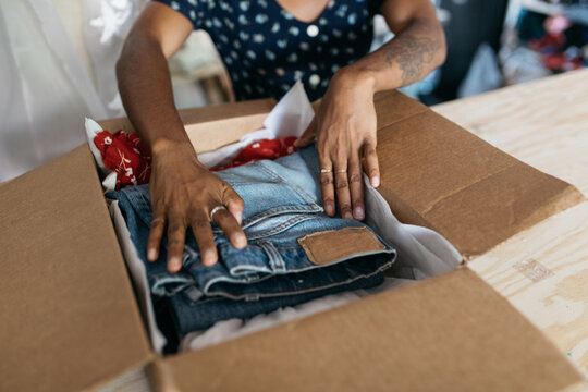 Young female business owner fashion entrepreneur packing clothing in box subscription delivery service