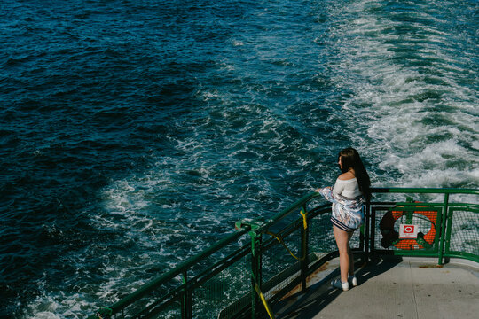 young woman standing at back of deck on a ferry