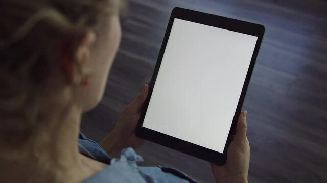 Woman holds tablet device in portrait orientation with blank white screen