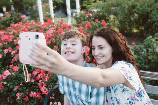 A young man with down syndrome spends a summer day taking pictures with his sister outside