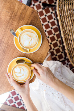 Top down view of hands holding coffee in cafe