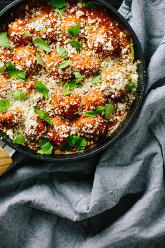 Baked Italian meatballs with parmesan and torn basil leaves