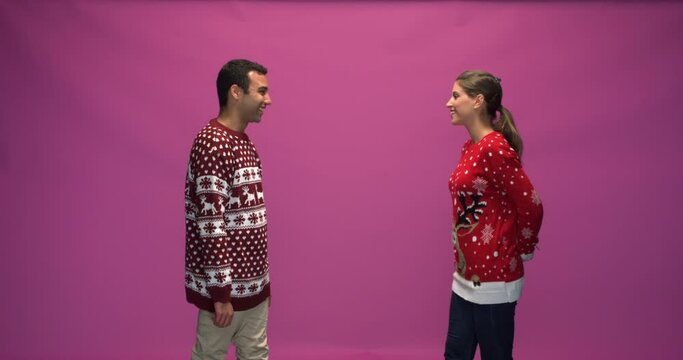 Studio, slow motion, young woman walks up to her friend with a mistletoe behind her back