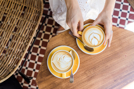 Top down view of hands holding coffee in cafe