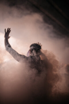 Anonymous protester dancing in mist during rave