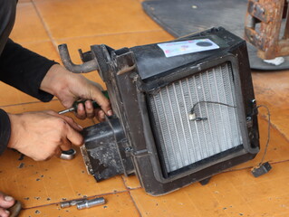 The car air conditioner mechanic is removing the cooling coil for rinsing.