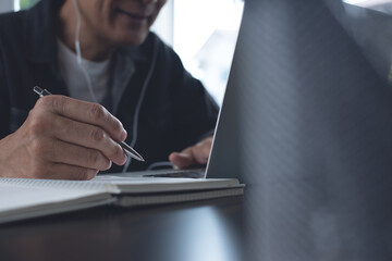 Student with earphone studying online via laptop computer at home, online learning concept 
