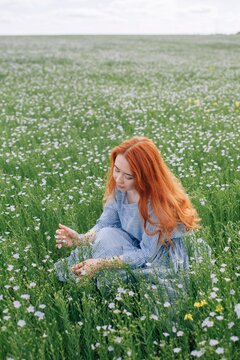 Lovely young female with long red hair enjoying time in summer field