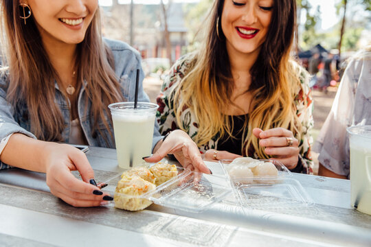 Women Share a Snack at Market