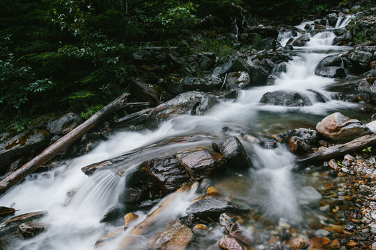 Gradually Cascading Waterfall Along Clear Stream In Green Forest