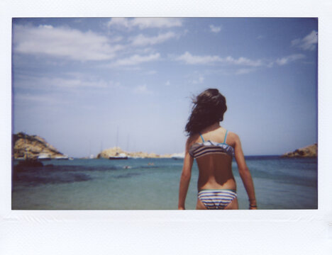 Back view of girl in striped bikini standing over seascape.