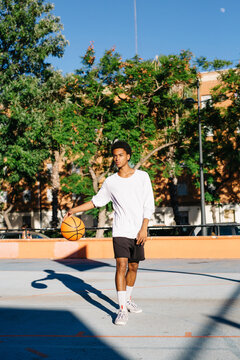 Black man playing basketball on street