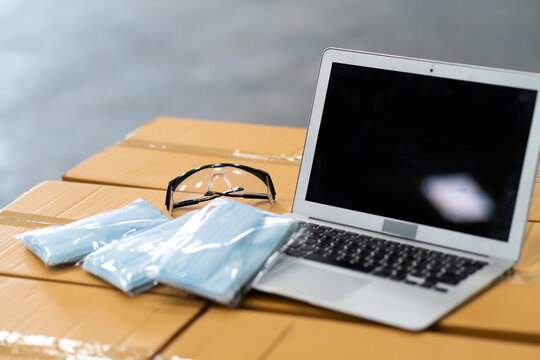 Face Mask, Laptop Computer And Goggle On Packing Box At Warehouse. Online Marketing, Startup SME, Freelance