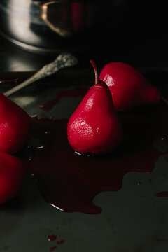 Red poached pears with blackberry and vanilla juice on baking tr