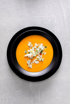 Crab bisque, in a black bowl on a tile background.
