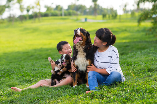 little asian boy holding his puppy sitting with his mother on th