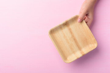 Betel palm leaf plate (Biodegradable plate, Compostable plate or Eco friendly disposable plate) holding by hand on pink background