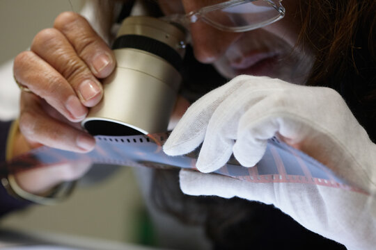 Woman with a magnifying loupe observing a negative motion film