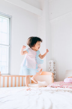 cute Chinese little girl jumpping on bed