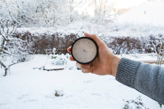 Hand holding thermometer measuring temperature in the winter