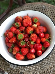 Strawberries in white bowl, rustic background. Soft focus