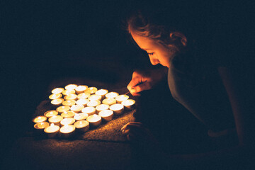 Teenage girl lighting tea lights in the form of a heart