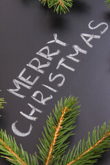 Inscription Merry Christmas and spruce branches on black background. Decoration for christmas time