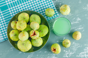 Green figs in a plate with drink flat lay on plaster and picnic cloth background
