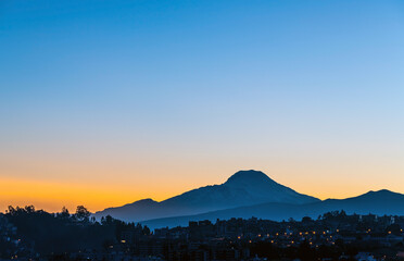 Quito city at sunrise with Cayambe volcano silhouette, Ecuador.