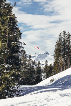 paraglider flying above snowcovered mountain landscape