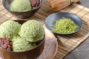 The homemade matcha ( Japanese green tea ) ice cream with red bean in the wooden bowl and put on bamboo mat.
