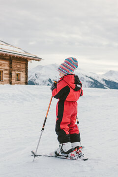 young boy on ski in front of an alpine cabin in snowcovered mountain landscape