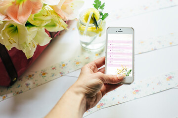 Hand holding a mobile phone checking her daily schedule